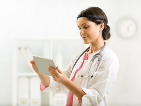 A doctor uses an iPad to enter information about a patient with chronic conditions.